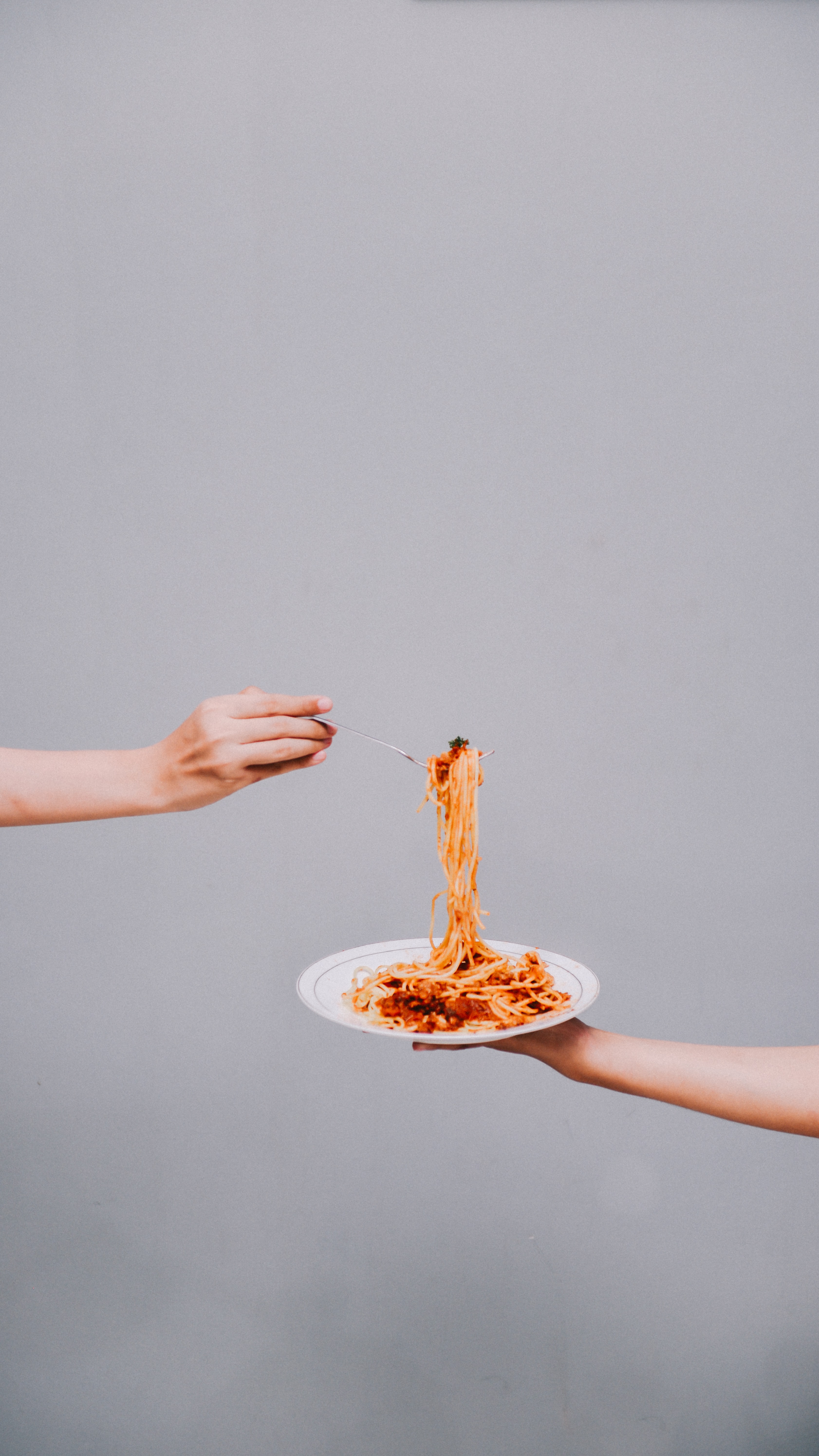 Someone sharing a plate of pasta with someone else